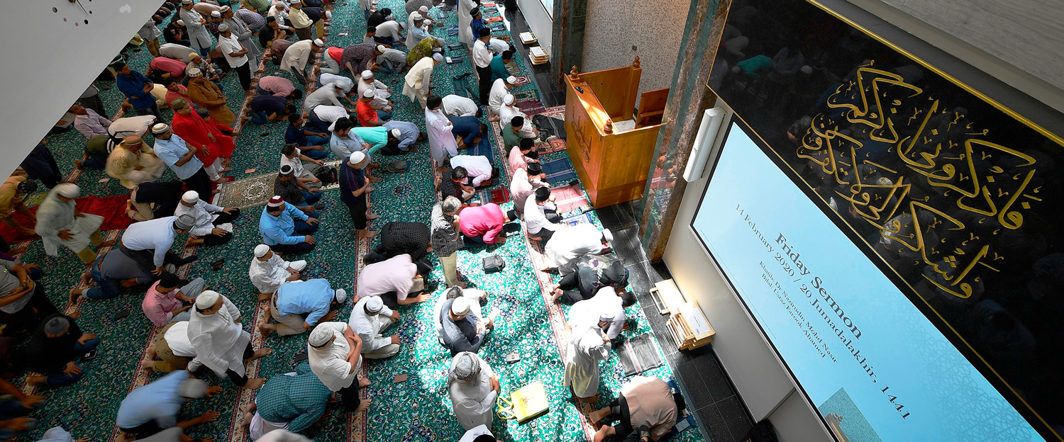 Main prayer hall with video projected on screen showing sermon text and live video of worshipers