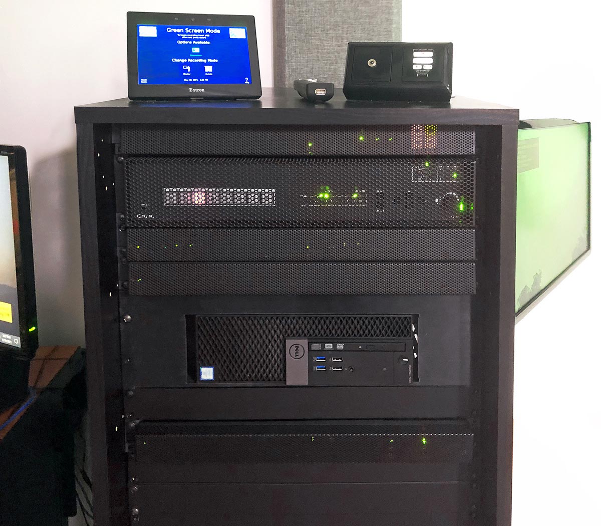 Main AV equipment rack. TLP Pro 725T 7” TouchLink Pro touchpanel, RCP 101 remote control panel, and presenter's remote control are on top of the rack. Visible within the rack are the IN1608 xi scaling presentation switcher and the PC. A confidence monitor swings out from the right side of the rack.