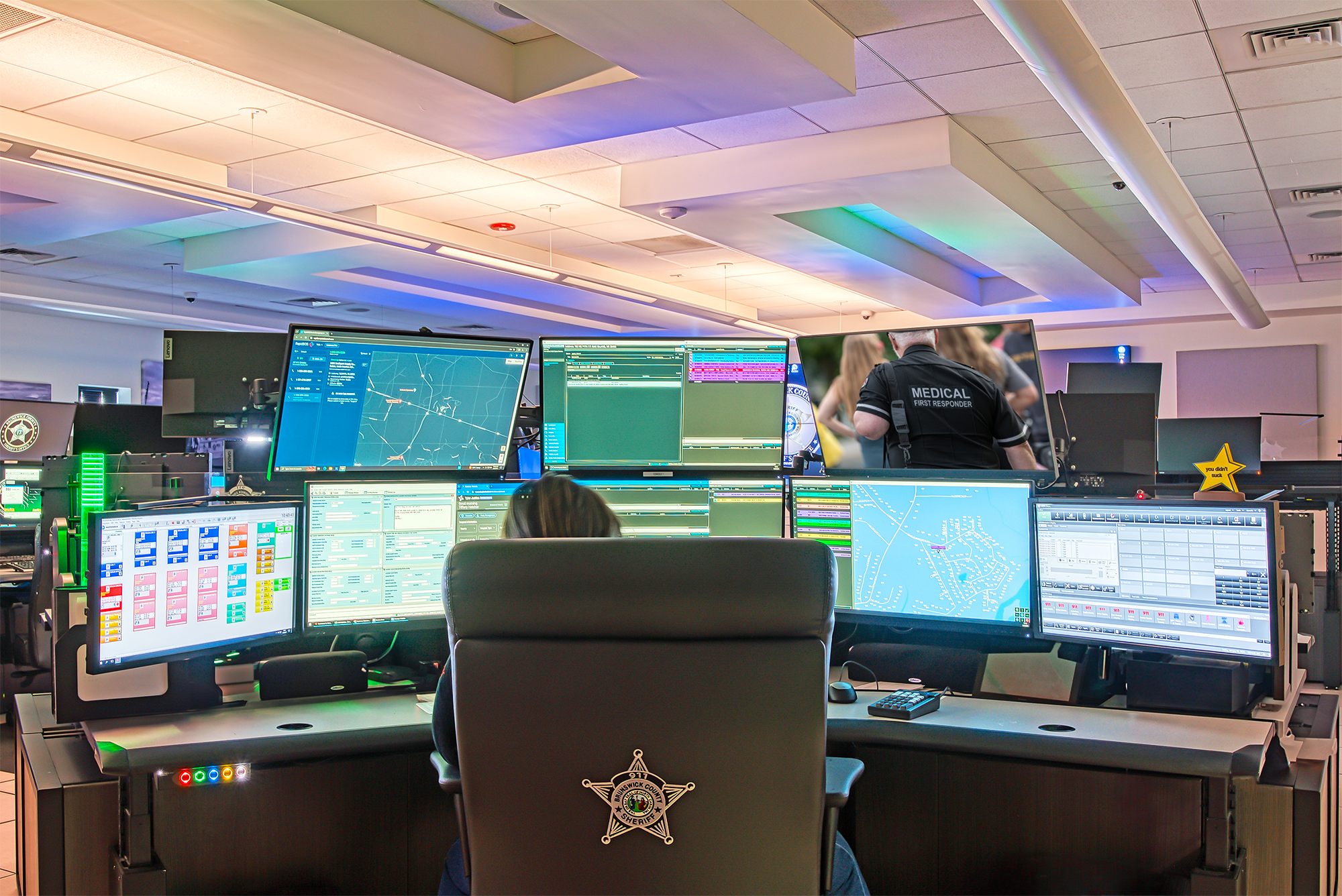 Each 911 workstation includes four consoles, one each for the radio dispatch system, the phone system, a CAD PC, and a browser PC, with Extron DTP Series transmitters and receivers delivering the AV signals to the eight local displays and touch screens.