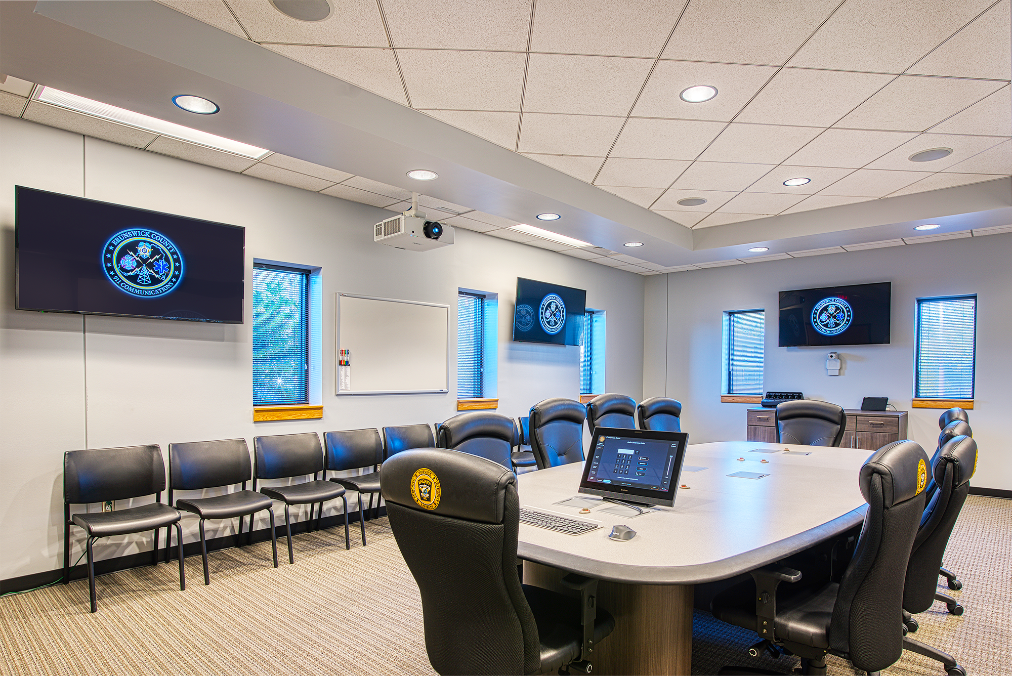 The conference room adjacent to the 911 call center has access to the same resources as the workstations over the NAV system and includes AV and USB data connectivity at the table.