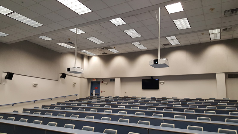 A flat panel display mounted on the back wall of a classroom