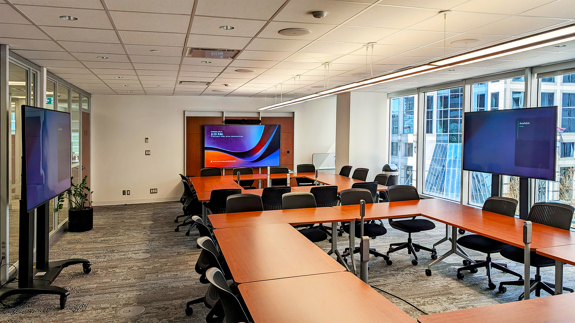 The room’s central wall-mounted display, complemented by stand-mount displays on either side, provides an immersive experience for both presentations and video conferences.