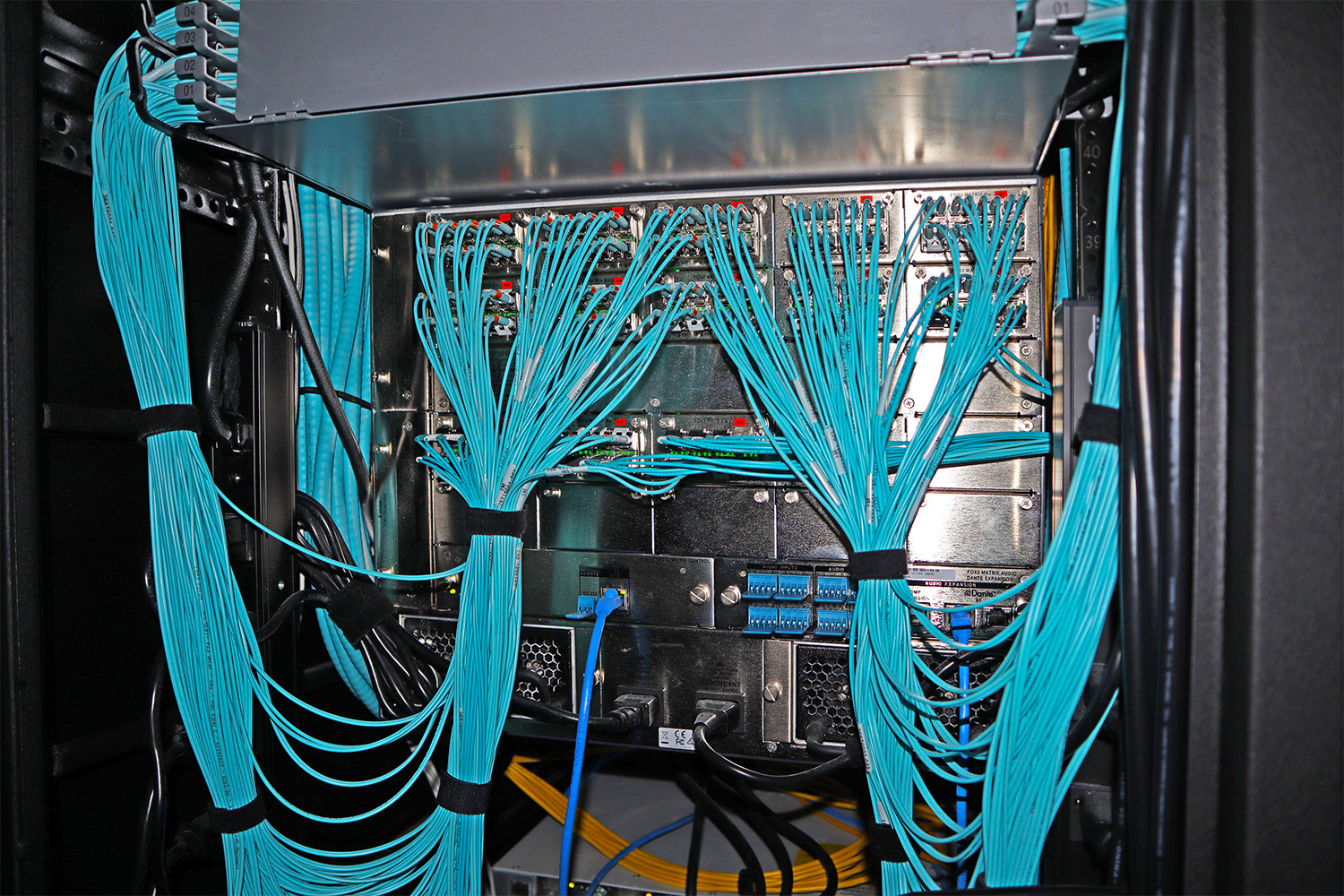 The multimode fiber optic cables are properly dressed at the racks, and the infrastructure links spaces within the EOC, enabling overflower and selectable content sharing by room.