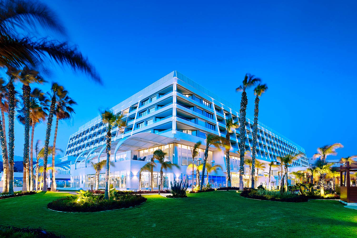 Outside view of Parklane Resort and Spa, corner view, surrounded by green grass and palm trees