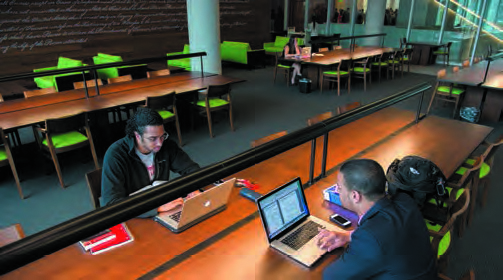 Two students studying while seated at a long table