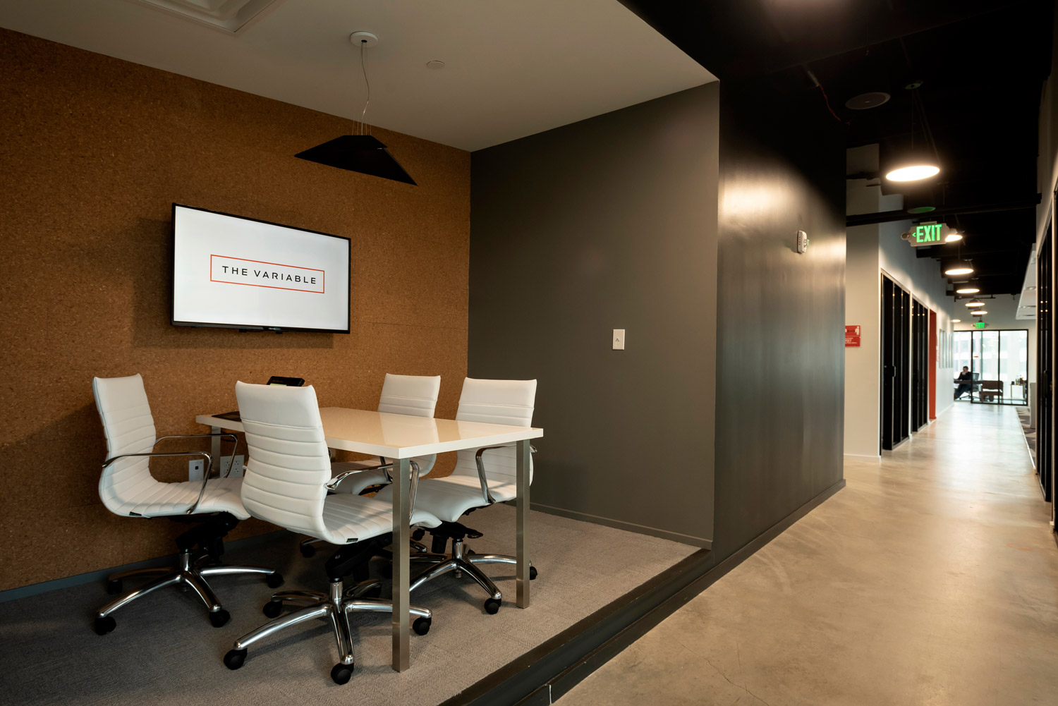 An office hallway with a conference table and a digital wall display.