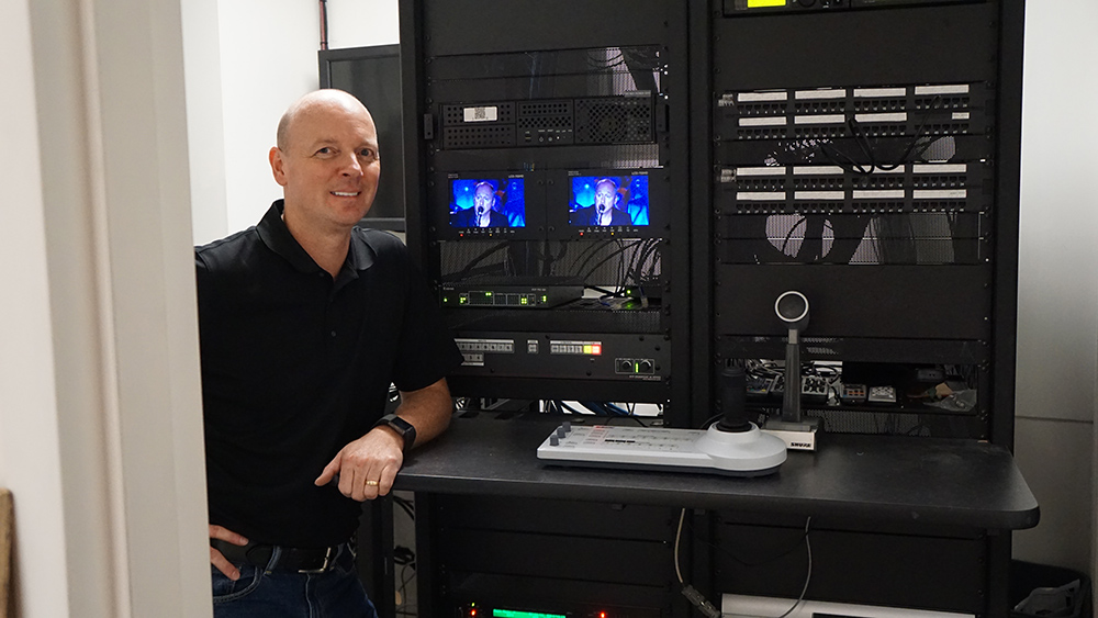 Robert E. Kennedy standing next to Extron Pro Series control system