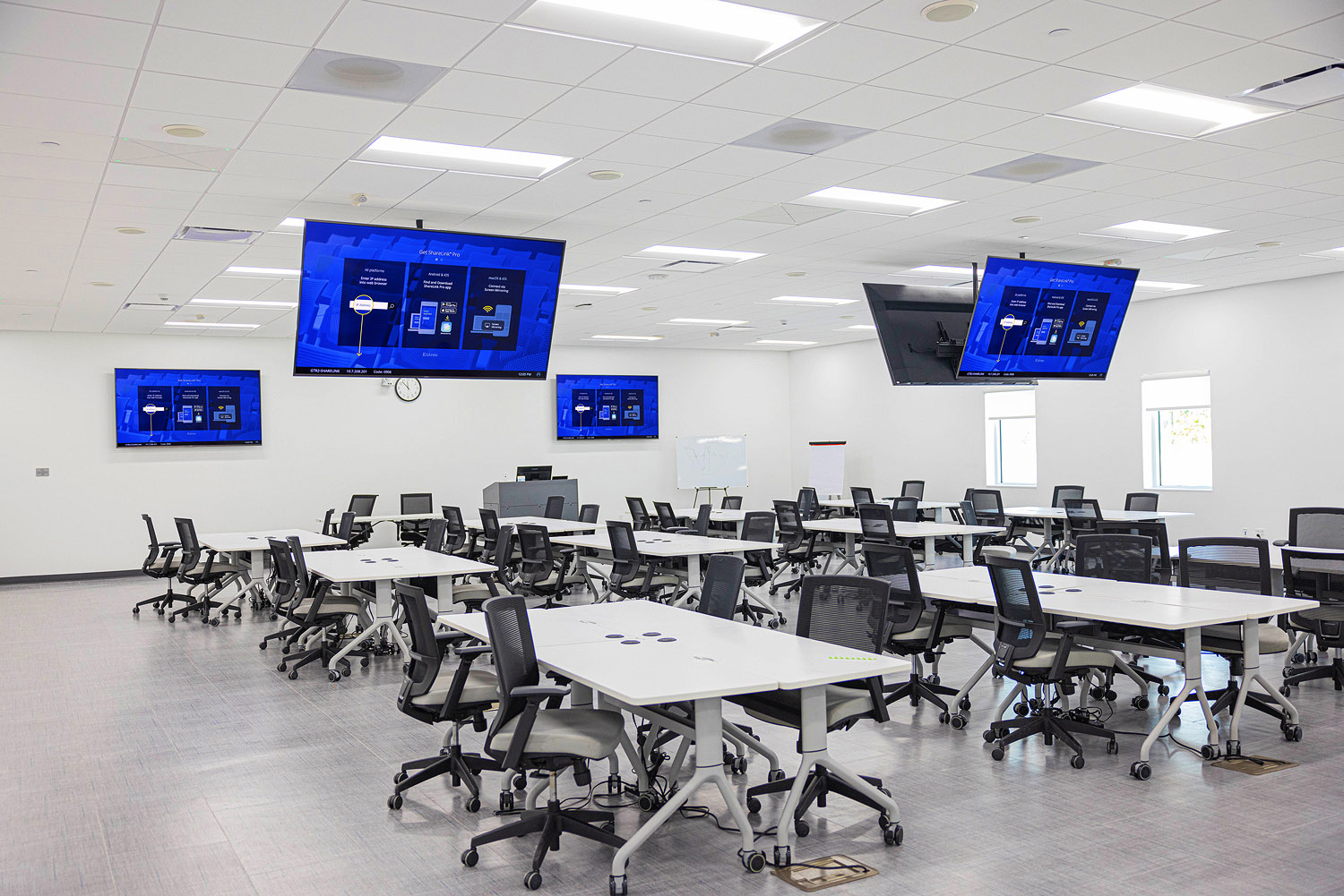 Two main classrooms for collaborative learning equipped with seven displays, nine ceiling array microphones, three PTZ cameras, two Extron ShareLink Pro 1100 Wireless Presentation Systems, and one Extron SMP 351 Streaming Media Processor, all connected via Extron NAV Pro AV over IP.