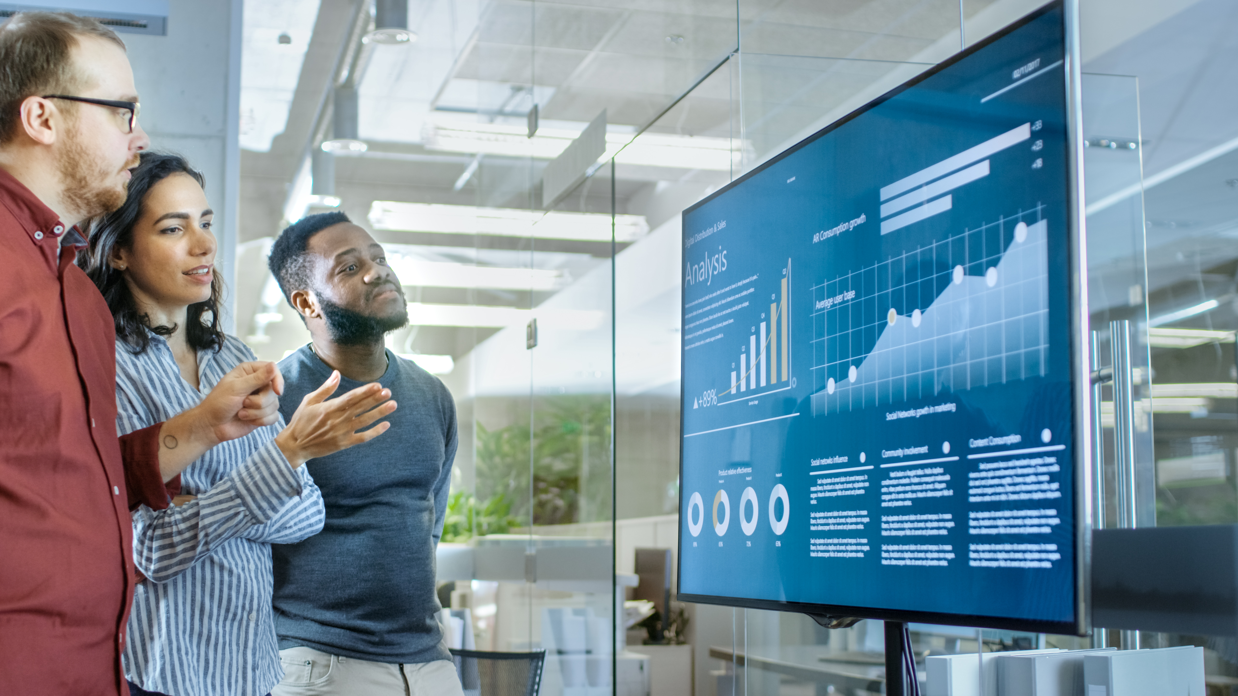 Three people staring at a large monitor