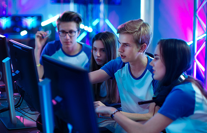 Four students working together and looking at the same desktop screen.