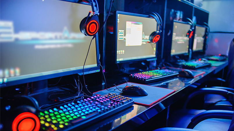 A row of gaming computers, headphones, and chairs.