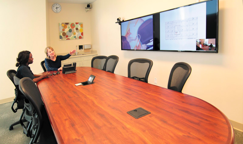 A debriefing room in a nursing school with two participants looking at two wall mounted displays.